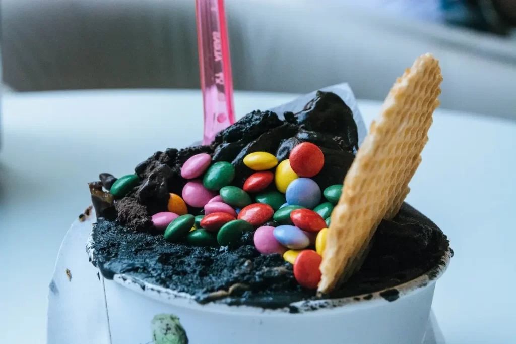 بستنی شکلاتی که بر روی آن بیسکویت و شکلات های رنگی کوچیک بر روی ان قرار دارد