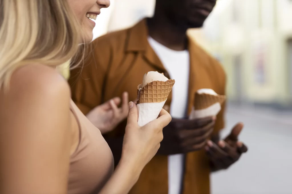 زن و مردی که در کنار هم ایستاده اند و درحال خوردن بستنی قیفی شکلاتی نانی میباشند